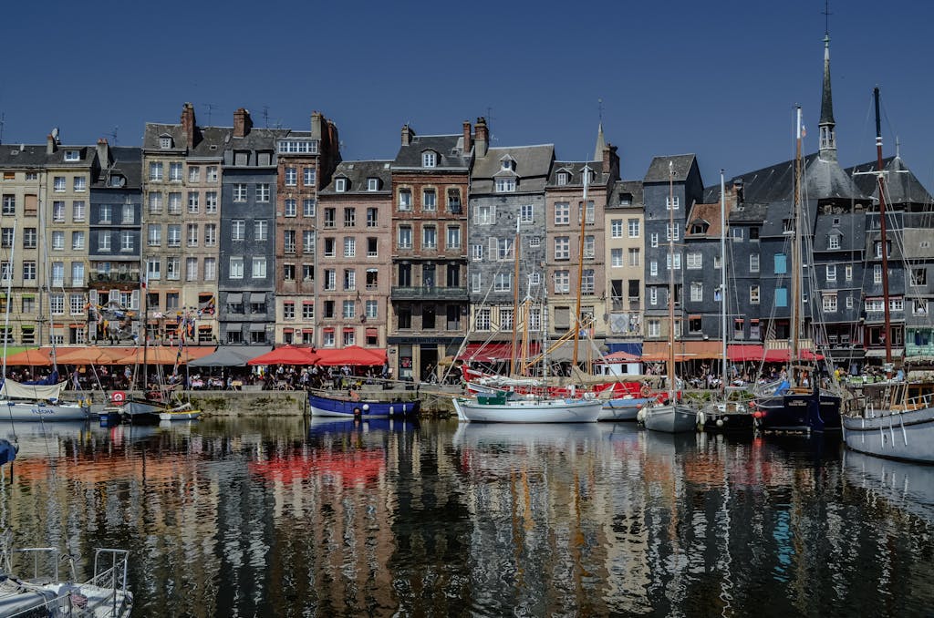 Colorful traditional buildings and sailboats in Honfleur, France's historic port.