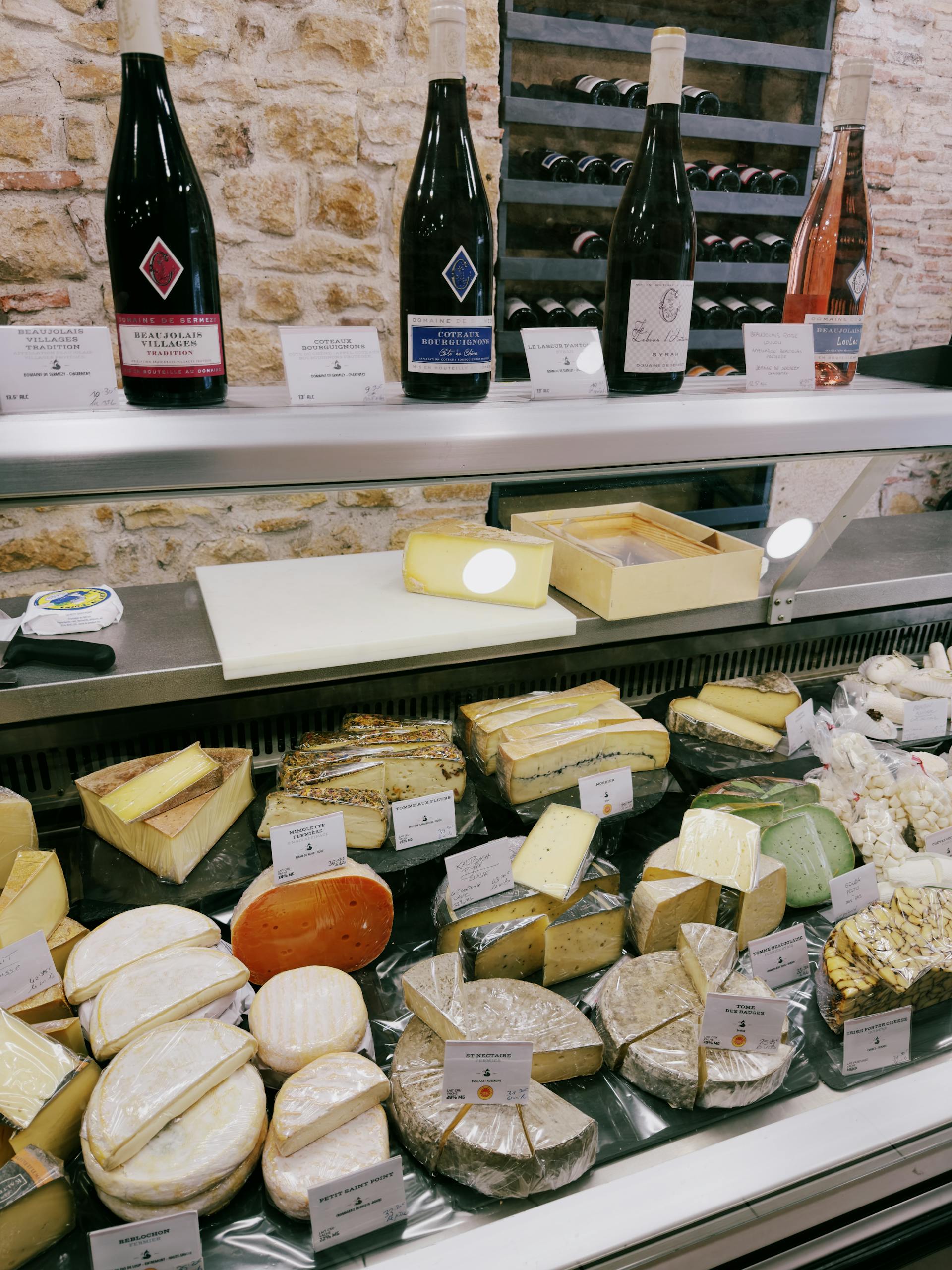 Explore a gourmet display of diverse French cheeses and wines captured in Villefranche-sur-Saône.
